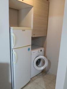 a small kitchen with a white refrigerator and a washing machine at ΤΑ ΩΡΑΙΑ ΤΗΣ ΑΘΗΝΑς in Skala Mistegnon