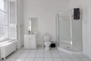 a white bathroom with a shower and a toilet at Comfort Room - Hotel Le Cavalier by M11 in Quebec City