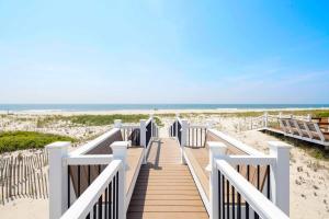 una passerella che porta alla spiaggia con l'oceano sullo sfondo di Dunecrest by RoveTravel - Family Oceanfront with Heated Pool a Westhampton Beach