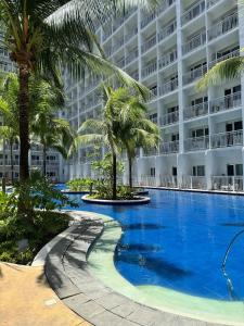 a large swimming pool with palm trees in front of a building at Relax in Pasay Citys Best Kept Secret - Spacious Condo with Garden View in Manila