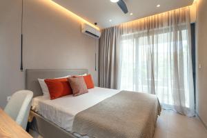 a bedroom with a bed with orange pillows and a window at Stylish Suite in Rhodes Town