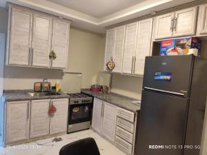 a kitchen with white cabinets and a black refrigerator at فيلا بيت الجبل in Ishtafaynā