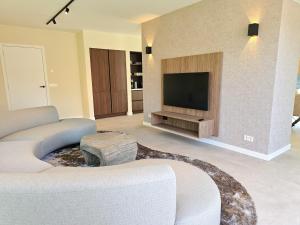 Una sala de estar con un sofá y un televisor. en Luxe vakantievilla BG04, en Biggekerke