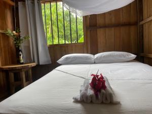 a white bed with a pile of towels on it at Posada El Cangrejal in Nuquí