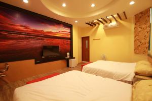 una camera d'albergo con due letti e una TV a schermo piatto di G Home Sir B&B a Magong