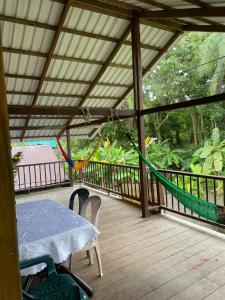 a hammock on a deck with a table and chairs at Posada El Cangrejal in Nuquí