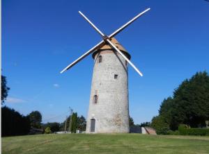 un molino de viento en un campo con un cielo azul en Duplex tout confort, en Marpent