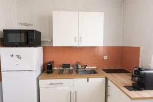 a kitchen with a sink and a white refrigerator at Appartement avec parking La Flocellière in La Flocellière