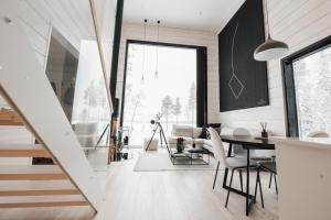 a dining room and living room with a table and chairs at Polaris Villas - Villa BLÄKK in Muonio
