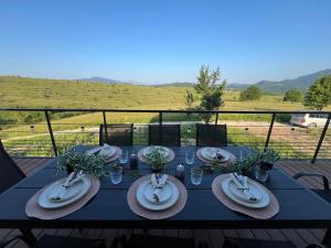 a blue table with plates and glasses on top of a field at TriPeak in Bjelašnica