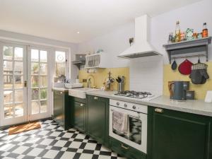 a kitchen with green cabinets and a checkered floor at Elm Cottage in Moreton in Marsh +20 photos