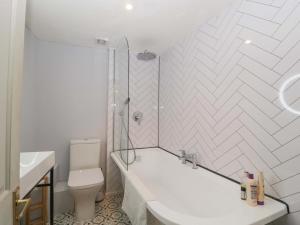 un bagno bianco con vasca e WC di Elm Cottage a Moreton in Marsh Altre 19 foto