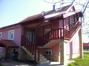 ein rosafarbenes Haus mit einer Treppe und einem Balkon in der Unterkunft Apartman Anka in Ratkovica