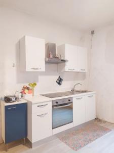 cocina con armarios blancos y horno azul en Antica Casa Montengian, en Pergine Valsugana