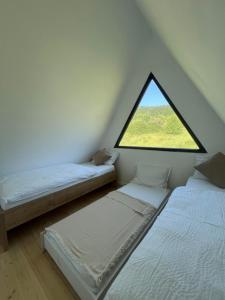 two beds in a room with a window at TriPeak in Bjelašnica