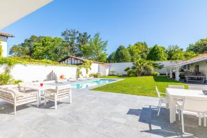 eine Terrasse mit Tischen und Stühlen neben einem Pool in der Unterkunft Villa Noa - Superbe villa piscine 8 personnes in Biarritz