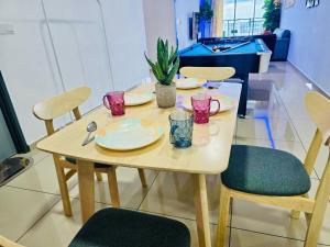 une table et des chaises avec des assiettes et des verres dans l'établissement Modern Family-Fun Suites - Infinity Pool, Ps5, Pool table, Indoor-Cinema with Balcony - M1, à Bukit Mertajam