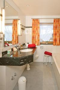ein Badezimmer mit einem Waschbecken, einem WC und einer Badewanne in der Unterkunft Hotel Landhaus Feldmeier ***S in Oberammergau