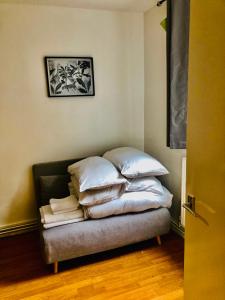 una pila de almohadas en una cama en una habitación en Little apartment 20 min from central London, en Londres 5 fotos más