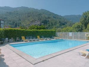 a swimming pool with chairs and a mountain in the background at ALojamento Costa da Banga in Geres