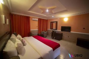 ein Hotelzimmer mit einem großen Bett und einem Fernseher in der Unterkunft Ubiq Suites and Apartments - Abuja in Abuja