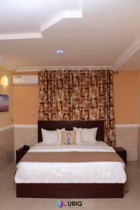 ein Schlafzimmer mit einem großen Bett mit einem hölzernen Kopfteil in der Unterkunft Ubiq Suites and Apartments - Abuja in Abuja