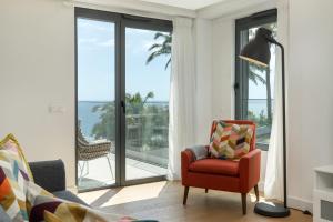 ein Wohnzimmer mit einem roten Stuhl und Glasschiebetüren in der Unterkunft Acqua Residence VIII by An Island Apart in Funchal + 33 Fotos