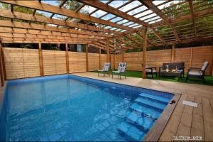 a swimming pool with two chairs and a pergola at בקתות טוסקנה רמות in Moshav Ramot