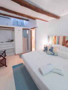 a bedroom with a white bed with a blue rug at Casa Turquesa in Los Roques