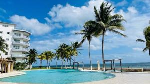 a swimming pool at the beach with palm trees and a building at Hermoso condominio in Cancún