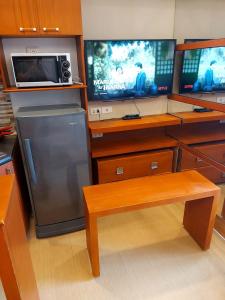a kitchen with two televisions and a refrigerator at Great Location, Swimming pool, Shops, Staycation in Iloilo City