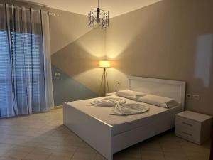 a bedroom with a white bed with a light on it at Simple Apartment in Orikum