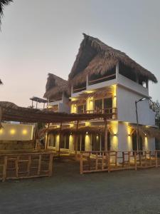 El Paredón Buena VistaLemon Tree El Paredon的一座带稻草屋顶的大型白色建筑