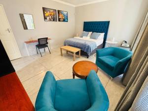 a bedroom with a bed and a blue couch and chairs at Dulelo Guest House Gaborone in Gaborone +41 photos
