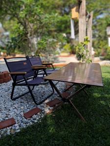 two chairs and a picnic table in the grass at บ้านเป็ดน้อย Little duck cottage in Ban Khlong Yang