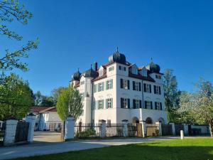 a large white house with a fence in front of it at Schloss Elmischwang in Fischach