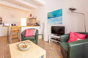 a living room with two green chairs and a television at Le Molire - Historical stone house in old Pzenas in Pézenas