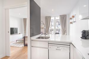 Biała kuchnia ze zlewem i salon w obiekcie Charming 1-Bedroom Apartment in Central Madrid Stylish Retreat for 2, Alonso Martinez I w Madrycie