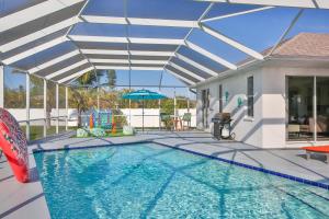 - une piscine avec un parasol et une maison dans l'établissement Tropical Reef, à Bradenton