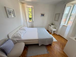 a white bedroom with a bed and a chair at Rooms Old Town in Rab