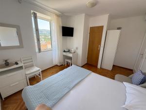 een slaapkamer met een bed, een bureau en een raam bij Rooms Old Town in Rab