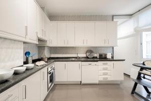 a white kitchen with white cabinets and a sink at Genteel Home Albareda in Seville +8 photos
