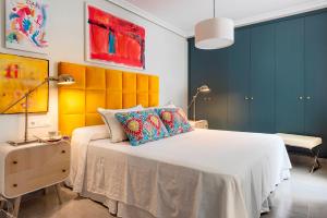 a bedroom with a large white bed with colorful pillows at Genteel Home Albareda in Seville