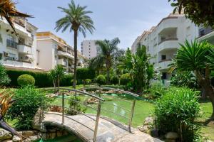 een brug over een tuin met palmbomen en gebouwen bij Las Palmeras BlueFish in Benalmádena