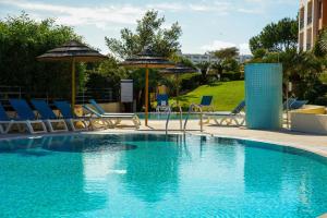 a swimming pool with chairs and umbrellas at Apartamento Panoramico - By Dalma Portuguesa in Branqueira