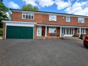 a brick house with a green garage door at High House View in Rubery