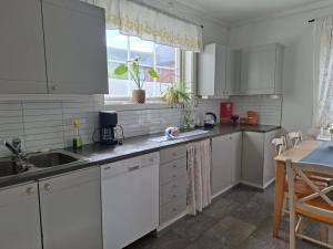 a kitchen with white cabinets and a sink and a window at Privat leilighet på gård med badstue og nordlys in Narvik +26 photos