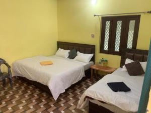 a bedroom with two beds with white sheets at Hotel Abhinandan in Phata