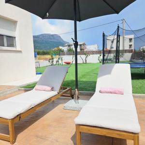 zwei Betten auf einer Terrasse mit Sonnenschirm in der Unterkunft SunN Joy in Kaštela