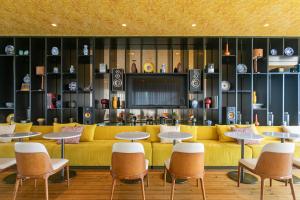 a living room with a yellow couch and tables and chairs at Octant Ponta Delgada in Ponta Delgada